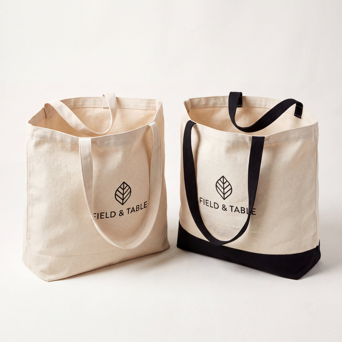 Natural and two-tone black cotton canvas tote bags with long handles and a sample black logo.