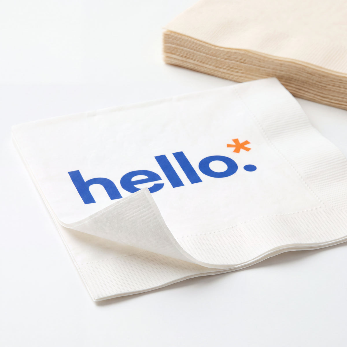 Close-up of a printed white paper napkin showing the embossed border and thin paper layers.